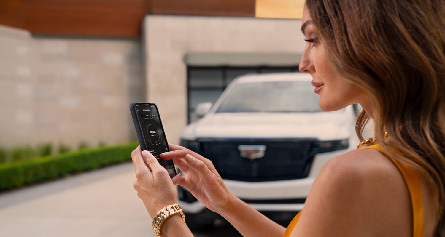 lady checking her mobile with a Cadillac vehicle background | Carlisle Cadillac in Carlisle PA